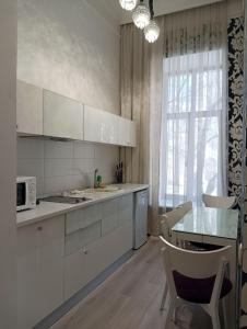 a kitchen with white cabinets and a table and a window at Hotel Menshikov in Odesa