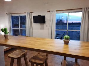 een eetkamer met een houten tafel en een groot raam bij Finca Los Racimos - Casa Syrah in San Rafael