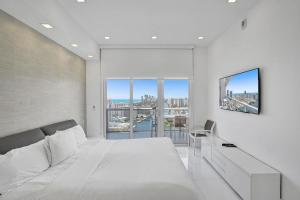 1 dormitorio con cama blanca y ventana grande en Modern Penthouse condo with 2 story private terrace, en Hollywood