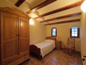 1 dormitorio con 1 cama, armario y silla en CAN CALCETER, en El Castell
