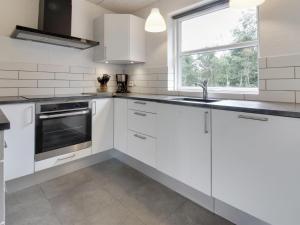 cocina con armarios blancos, fregadero y ventana en Holiday Home Jarven - 500m to the inlet in The Liim Fiord by Interhome, en Højslev