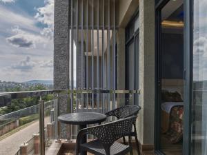 einen Balkon mit einem Tisch, Stühlen und einem Bett in der Unterkunft Unique Apartment in Kigali