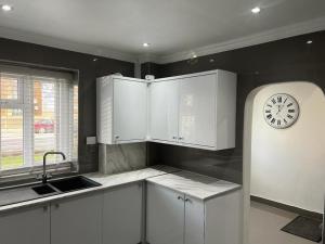a kitchen with white cabinets and a clock on the wall at Modern Executive 2-Bed Apartment in London in London
