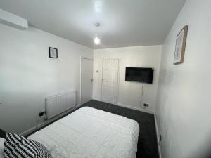 a white bedroom with a bed and a tv at Modern Executive 2-Bed Apartment in London in London