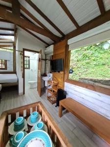 a living room with a couch and a table with dishes at Chalé Paúba 80m do Mar in Pauba