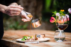 Eine Person gießt Wein in einen Teller mit Essen. in der Unterkunft Landgoed Rhederoord nabij Arnhem in De Steeg