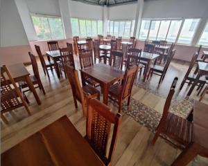 um restaurante com mesas e cadeiras de madeira e janelas em T Homes Thekkady em Thekkady