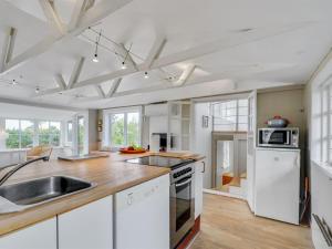 a kitchen with white appliances and wooden floors at Holiday Home Gren - 90m to the inlet in The Liim Fiord by Interhome in Roslev