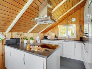 Il comprend une cuisine avec des placards blancs et un plafond en bois. dans l'établissement Holiday Home Henrieke - 250m to the inlet in The Liim Fiord by Interhome, à Roslev
