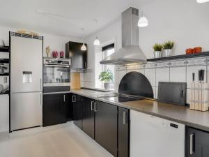 cocina con armarios blancos y negros y nevera en Holiday Home Imilie - 250m to the inlet in The Liim Fiord by Interhome, en Redsted