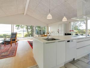 cocina con armarios blancos y comedor en Holiday Home Elissa - 50m to the inlet in The Liim Fiord by Interhome, en Roslev