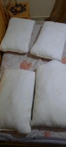 4 almohadas blancas sentadas encima de una cama en appartement à louer saidia, en Saidia 