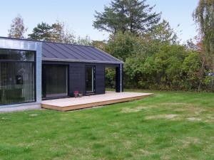 a black shed with a deck in a yard at Holiday Home Yukon - 150m from the sea in SE Jutland by Interhome in Odder