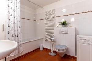 a white bathroom with a toilet and a sink at Appartementhaus Appartement Strandläufer in Süderhöft +22 photos