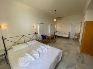 a bedroom with a bed with white sheets and a table at Hotel Plakures in Falasarna