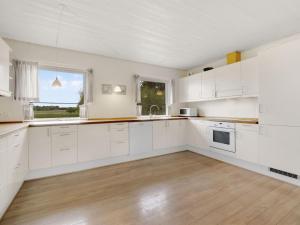 a kitchen with white cabinets and a wooden floor at Holiday Home Mikkeline - 400m to the inlet in The Liim Fiord by Interhome in Øster Assels