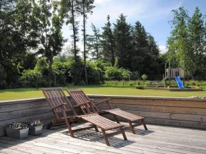 - deux chaises en bois assises sur une terrasse avec une aire de jeux dans l'établissement Holiday Home Etly - 600m to the inlet in The Liim Fiord by Interhome, à Roslev