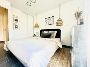 a bedroom with a large white bed with pendant lights at Les Jardins des Senteurs - Appartement privé avec piscine et parking in Grasse