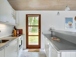 a kitchen with white cabinets and a wooden door at Holiday Home Morten - 500m from the sea in Djursland and Mols by Interhome in Ebeltoft
