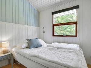 a white bedroom with a bed and a window at Holiday Home Morten - 500m from the sea in Djursland and Mols by Interhome in Ebeltoft