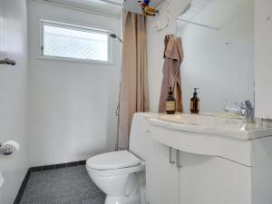 a white bathroom with a toilet and a sink at Holiday Home Morten - 500m from the sea in Djursland and Mols by Interhome in Ebeltoft