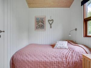 a bedroom with a bed with a pink blanket at Holiday Home Morten - 500m from the sea in Djursland and Mols by Interhome in Ebeltoft