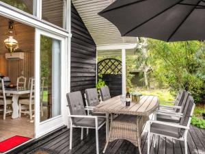 een patio met een tafel en stoelen en een parasol bij Holiday Home Fiallar - 7-5km from the sea in Djursland and Mols by Interhome in Rønde
