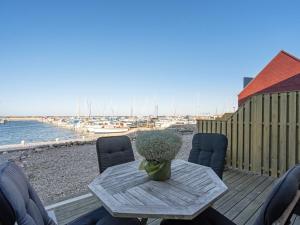 uma mesa com cadeiras e um vaso de flores num deque em Apartment Line - 10m from the sea in Djursland and Mols by Interhome em Glesborg