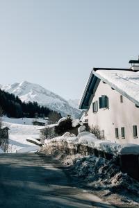 una casa está cubierta de nieve junto a una carretera en Charming chalet with sauna + views!, en Bad Gastein