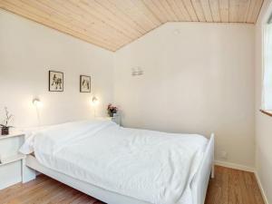 ein Schlafzimmer mit einem weißen Bett und einer Holzdecke in der Unterkunft Holiday Home Edele - 800m from the sea in Djursland and Mols by Interhome in Glesborg