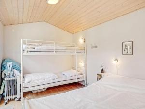 ein Schlafzimmer mit weißen Etagenbetten und einer Holzdecke in der Unterkunft Holiday Home Edele - 800m from the sea in Djursland and Mols by Interhome in Glesborg