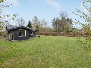 una casa negra en un campo con un patio en Holiday Home Sunja - 450m from the sea in Djursland and Mols by Interhome, en Brøndstrup