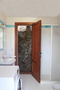 La salle de bains est pourvue d'une douche, d'un lavabo et d'une porte. dans l'établissement Villa Olivastro, à Torre delle Stelle