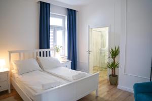 a bedroom with a white bed and a glass shower at RJ Family Sopot in Sopot