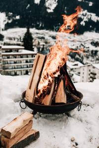 un fuego en una parrilla en la nieve en Charming chalet with sauna + views! en Bad Gastein