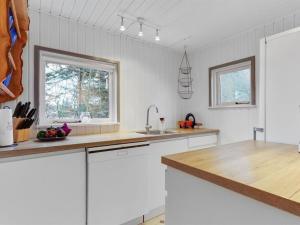 une cuisine avec des placards blancs et un comptoir en bois dans l'établissement Holiday Home Teofilka - 200m from the sea in NE Jutland by Interhome, à Sæby