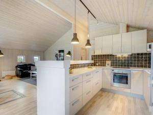 a kitchen with white cabinets and a living room at Holiday Home Femke - 250m to the inlet in NE Jutland by Interhome in Storvorde