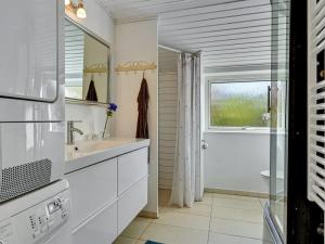 ein weißes Badezimmer mit einem Waschbecken und einem Spiegel in der Unterkunft Holiday Home Joon - 300m from the sea in Djursland and Mols by Interhome in Ørsted