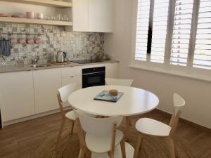 a white kitchen with a white table and chairs at Blue House By The Sea Adult Retreat in Kinross