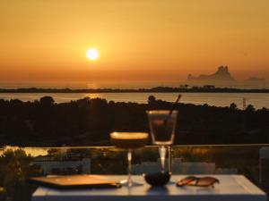 una mesa con una bebida y vistas a la puesta de sol en Five Flowers Hotel & Spa Formentera en Es Pujols