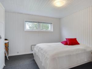 een witte slaapkamer met een rood kussen op een bed bij Holiday Home Nelda - 300m to the inlet in NE Jutland by Interhome in Storvorde