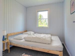 een slaapkamer met een houten bed en een raam bij Holiday Home Nelda - 300m to the inlet in NE Jutland by Interhome in Storvorde