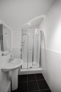 a white bathroom with a shower and a sink at Argyll Western Hotel in Glasgow