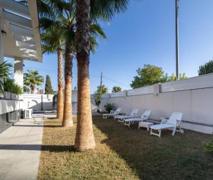 una fila de sillas blancas sentadas junto a una pared con palmeras en Exclusive Villa City, Beach & Golf, en Alicante
