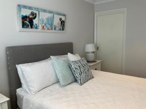 a white bed with pillows and a picture on the wall at Blue House By The Sea Adult Retreat in Kinross