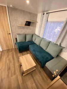 uma sala de estar com um sofá verde e uma mesa em Superbe Mobil home 6-8 personnes (57) em Saint-Jean-de-Monts