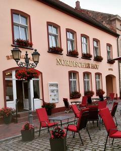restauracja ze stołami i krzesłami przed budynkiem w obiekcie Nordischer Hof w mieście Krakow am See