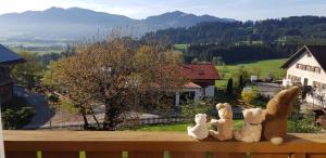 tres animales de peluche sentados en la parte superior de un banco de madera en Gästehaus Eckstein, en Oy-Mittelberg