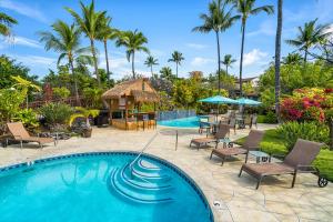 einen Pool mit Stühlen, einem Pavillon und Palmen in der Unterkunft Keauhou Resort 113 in Kailua-Kona
