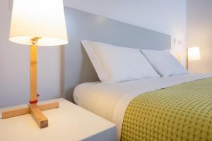 a bedroom with a bed and a lamp on a table at Bétula Studios in Bragança